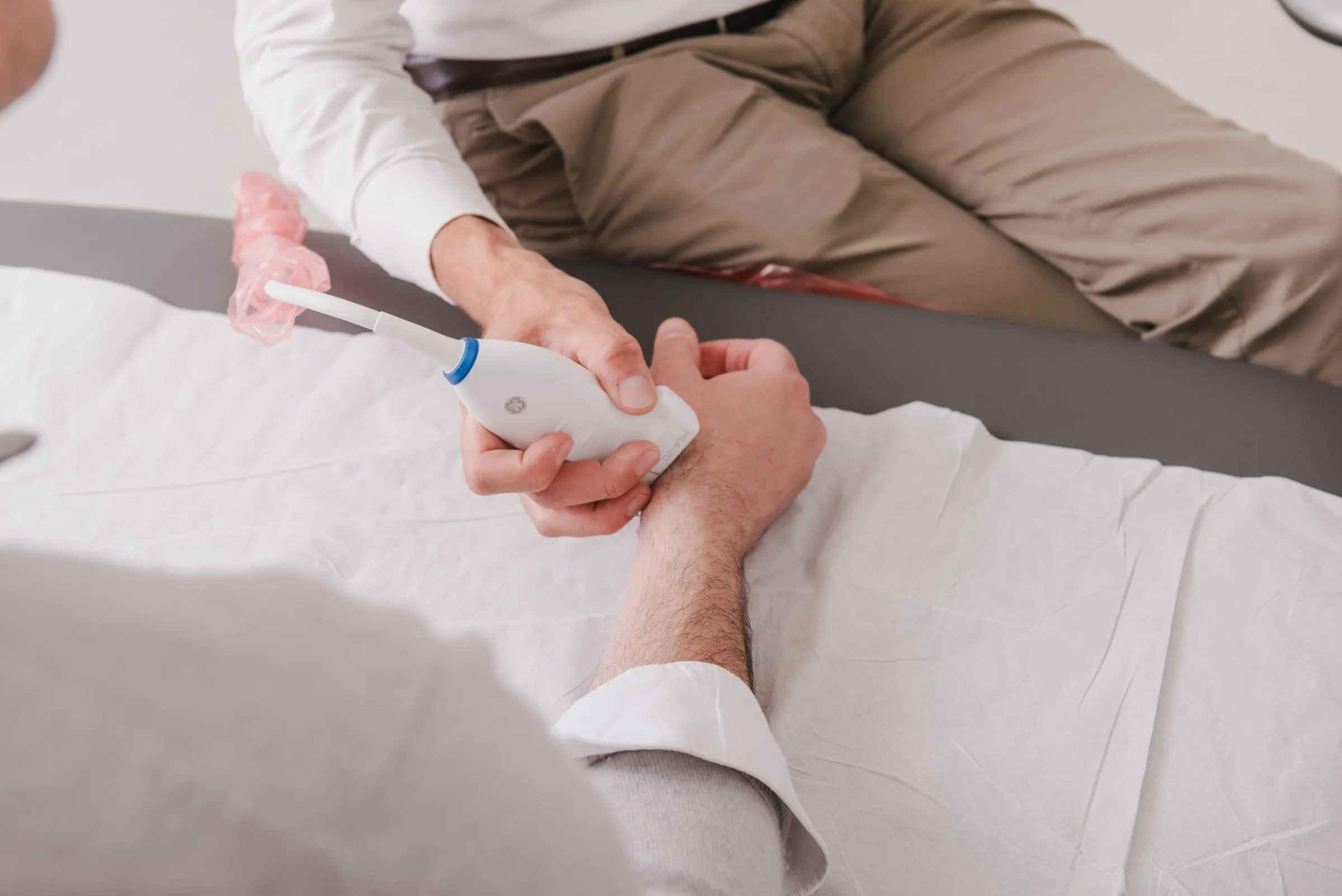 Radiologist running an ultrasound probe along a patient’s wrist